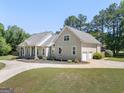 Gorgeous home with attached two-car garage and circular driveway surrounded by lush greenery at 207 Jamestown Ave, Jonesboro, GA 30236