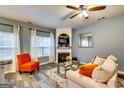 Cozy living room with fireplace, bright windows, wood floors, and a ceiling fan at 7750 Carnegie Dr, Fairburn, GA 30213
