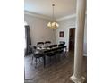 Formal dining room featuring an elegant chandelier, a dark table with six chairs, and wood flooring at 203 Collierstown Way, Peachtree City, GA 30269