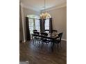 Bright dining room featuring chandelier, hardwood floors, and ample natural light from large windows at 203 Collierstown Way, Peachtree City, GA 30269