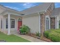 Inviting front porch with stone accents, lush landscaping, and a red front door at 203 Collierstown Way, Peachtree City, GA 30269