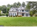 Inviting two-story home featuring a lush green lawn, beautiful landscaping, and a classic architectural design at 6205 Collingham Trce, Cumming, GA 30040