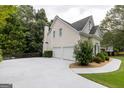 View of the home's rear exterior, showcasing a spacious three-car garage and well-maintained grounds at 6205 Collingham Trce, Cumming, GA 30040