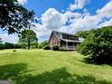 Brick home with a large, lush green lawn and a covered back porch, surrounded by mature trees and blue skies at 238 Marks Rd, Mansfield, GA 30055