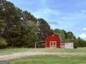 Quaint red barn featuring white doors and an attached covered area, nestled among tall trees at 238 Marks Rd, Mansfield, GA 30055