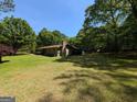 Exterior view of a green home with a brick chimney and a vast lawn surrounded by mature trees at 1710 Crumbley Rd, Mcdonough, GA 30252