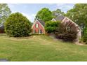 View of a brick home from across a spacious, green lawn with mature trees, highlighting its curb appeal at 1270 Tribble Walk Ct, Lawrenceville, GA 30045