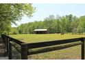 Fenced pasture with a barn and grazing animals, ideal for equestrian pursuits at 288 Trickum Creek Rd, Tyrone, GA 30290