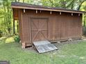 Backyard wooden shed with double doors, a ramp and brick supports at the corners at 96 Daniel Ct, Mcdonough, GA 30253