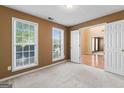 Bedroom with neutral carpet, two windows, and a view into the adjacent living area at 643 Rangeley Meadows Ct, Hampton, GA 30228