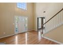 Bright foyer featuring hardwood floors, a staircase, and a view of the front door with sidelights at 643 Rangeley Meadows Ct, Hampton, GA 30228