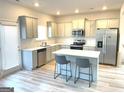 Bright kitchen with white cabinets, stainless steel appliances, an island and wood grain vinyl flooring at 169 Cabin Way, Hampton, GA 30228