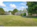 Spacious front yard showcasing a well-kept lawn and a charming house nestled among mature trees at 90 Harlin Ct, Covington, GA 30014