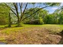 View of the front yard and exterior of the red home surrounded by mature trees and landscaping at 362 Highway 113, Temple, GA 30179
