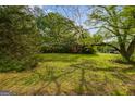 View of the front yard and exterior of the red home surrounded by mature trees and landscaping at 362 Highway 113, Temple, GA 30179