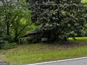 Quaint cabin exterior with mature trees, lush greenery, and covered porch at 3935 Jailette Rd, South Fulton, GA 30349