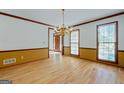 Formal dining room with a classic chandelier, hardwood floors, and natural light from two large windows at 2402 Creekside Trce, Jonesboro, GA 30236