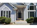 Inviting front entrance featuring a black door, sidelights, transom window, and manicured bushes at 109 Windsong Dr, Stockbridge, GA 30281