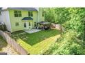 Expansive backyard featuring a well-maintained lawn, privacy fence, mature trees and a cozy patio area at 30 Saint Charles Pl, Sharpsburg, GA 30277