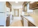 Kitchen featuring white appliances, brown cabinetry, and a stainless steel sink at 110 Tamarack Trl, Mcdonough, GA 30252