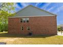 Rear view of a brick townhome featuring multiple windows and lush green lawn at 3526 Brockenhurst Dr, Buford, GA 30519