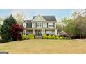 View of a traditional two-story home featuring a wide front lawn and a welcoming covered front porch at 109 Lighthorse Blvd, Mcdonough, GA 30252