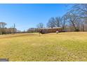 Spacious backyard featuring a well-manicured lawn, mature trees, and a charming home exterior at 461 Old Jackson Rd, Mcdonough, GA 30252