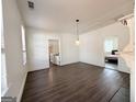Bright living room with hardwood floors, white walls, and modern light fixtures; a gateway to the kitchen and a bedroom at 30 Poplar St, Porterdale, GA 30014