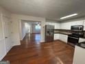 Open-concept kitchen with stainless steel appliances seamlessly flowing into the living space with hardwood flooring at 435 Cedarhurst Rd, Lawrenceville, GA 30045