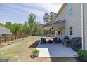 Serene backyard featuring a covered patio with outdoor seating and a lush green lawn at 7435 Ansley Park Way, Cumming, GA 30028