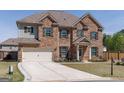 Charming two-story brick home boasts a well-manicured lawn, a two-car garage, and classic architectural details at 7435 Ansley Park Way, Cumming, GA 30028