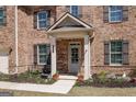 Inviting front porch with decorative wreath, fresh flowers, and a cozy bench, adding charm to this brick home at 7435 Ansley Park Way, Cumming, GA 30028