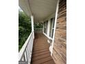 Inviting front porch featuring stone accents, wood flooring, and white railing overlooking the lush greenery at 22 Shea Ct, Douglasville, GA 30134