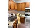 Galley kitchen with wood cabinetry, stainless steel sink, and white appliances at 3464 Kingswood Trl, Decatur, GA 30034