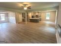 Open floor plan featuring a living room with sleek flooring, ceiling fan, and flows into a kitchen with gray cabinetry at 165 Jodi Pl, Locust Grove, GA 30248
