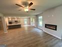 Spacious living room featuring sleek hardwood floors, a ceiling fan, and a modern fireplace insert for a cozy ambiance at 165 Jodi Pl, Locust Grove, GA 30248