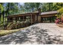 Charming cabin-style home with brick foundation, an attached carport, and lush, mature landscaping at 20 King Pl, Stockbridge, GA 30281