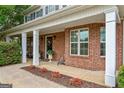Inviting front porch with brick columns, flower beds, and a decorative front door at 220 Calli Ct, Mcdonough, GA 30252
