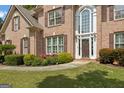 Close-up of a brick home with an arched entryway, trimmed shrubs, and well-kept lawn at 891 Berryman Pl, Lawrenceville, GA 30045