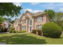 Brick home with manicured lawn and mature trees, features a side view of neighboring property at 891 Berryman Pl, Lawrenceville, GA 30045