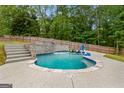 Backyard in-ground pool with waterfall feature, stone accents, and wooded surroundings at 608 Bellenden Dr, Peachtree City, GA 30269