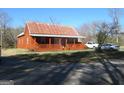 Cozy red cabin featuring a covered porch, a metal roof, and an adjacent gravel driveway at 526 Mount Carmel Church Rd, Temple, GA 30179