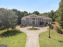 Aerial view of a brick home with landscaped grounds and a circular driveway and statue at 320 Riverbend Dr, Mcdonough, GA 30252