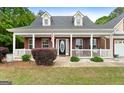 Inviting front porch featuring rocking chairs, an American flag, and well-maintained landscaping at 563 Deadwood Trl, Locust Grove, GA 30248