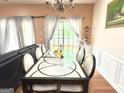 Elegant dining room featuring a modern chandelier, wainscoting, and a large glass-top table at 3311 Thornbridge Dr, Powder Springs, GA 30127