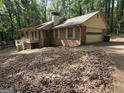 View of a two-story home featuring a brick facade and a side-entry garage nestled among trees at 4081 Jodeco Rd, Stockbridge, GA 30281