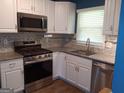 Modern kitchen features stainless steel appliances, granite counters, and white cabinets at 4616 Hamlet Se Walk, Conyers, GA 30094