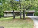 A single-Gathering home with an attached garage is surrounded by lush green trees and a well-manicured lawn at 110 Thompson Blvd, Stockbridge, GA 30281