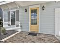 Close up of a yellow front door with glass panels, flanked by black sconces and a brick porch at 307 Owenberg Trce, Peachtree City, GA 30269