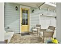 Charming yellow front door, brick porch, and comfortable seating area at 307 Owenberg Trce, Peachtree City, GA 30269